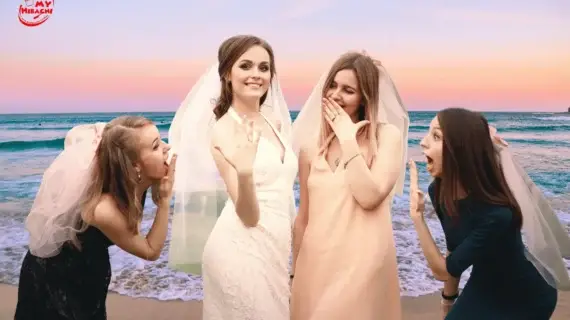 group of four women celebrating a bachelorette party on the beach at sunset. The bride, wearing a white dress and veil, proudly shows her engagement ring while her friends, also wearing veils, react with excitement and laughter.